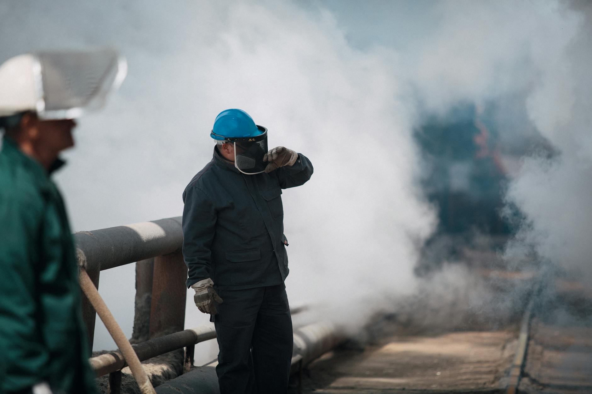 Industrial workers wearing protective gear surrounded by heavy smoke, ensuring safety in harsh environments.