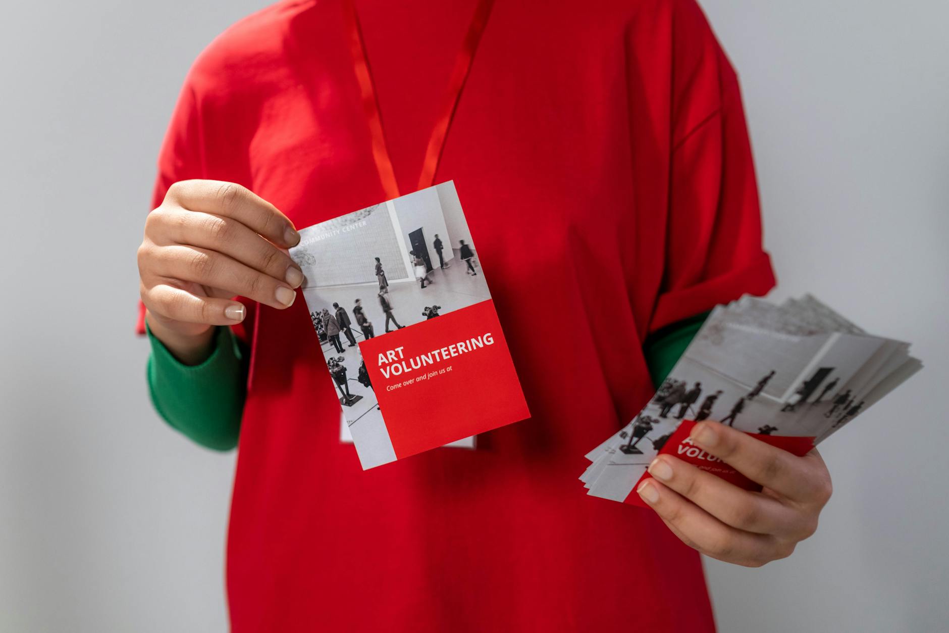 Close-up of a volunteer holding art volunteering flyers highlighting community service.